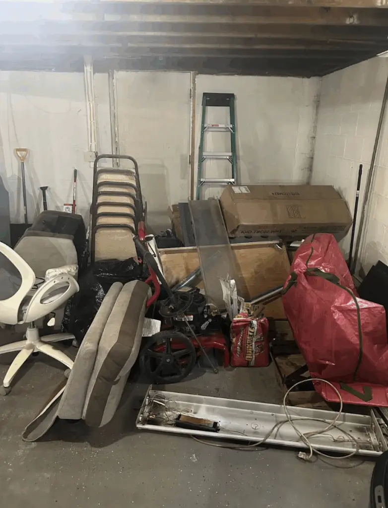 Basement clean out project with furniture, tools, and bulky junk ready for removal in Elmira, NY.