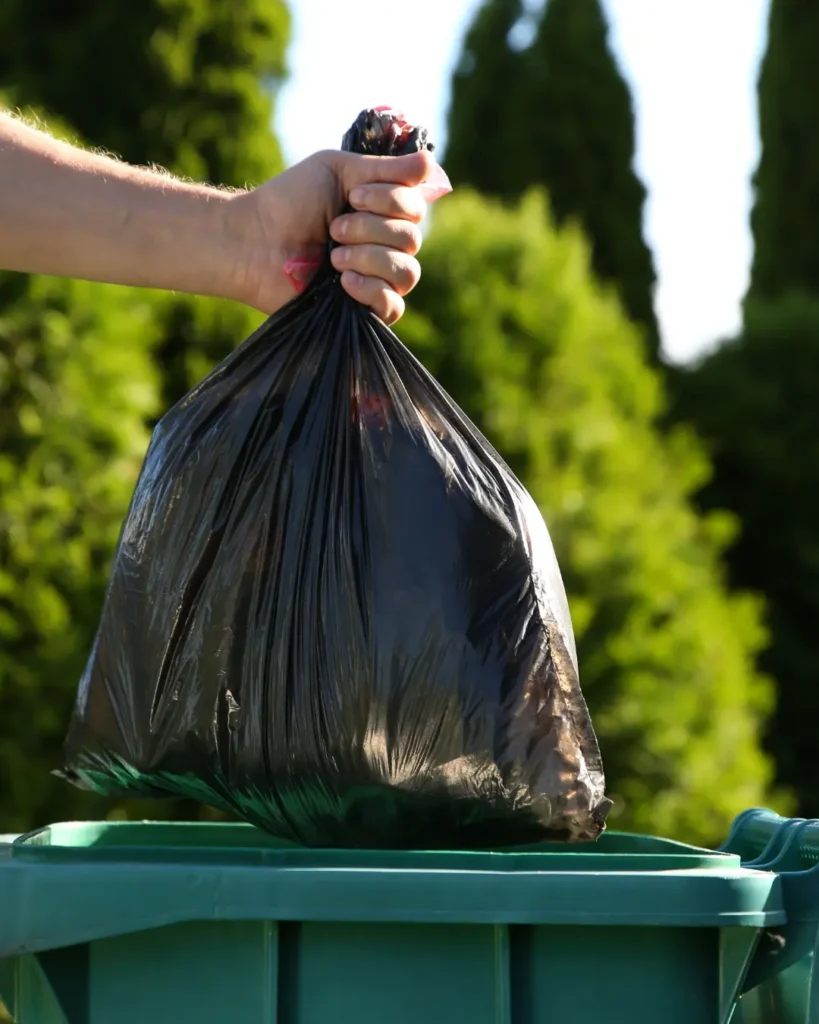 Bagged household trash going into a curbside bin for weekly trash pickup in Corning, NY